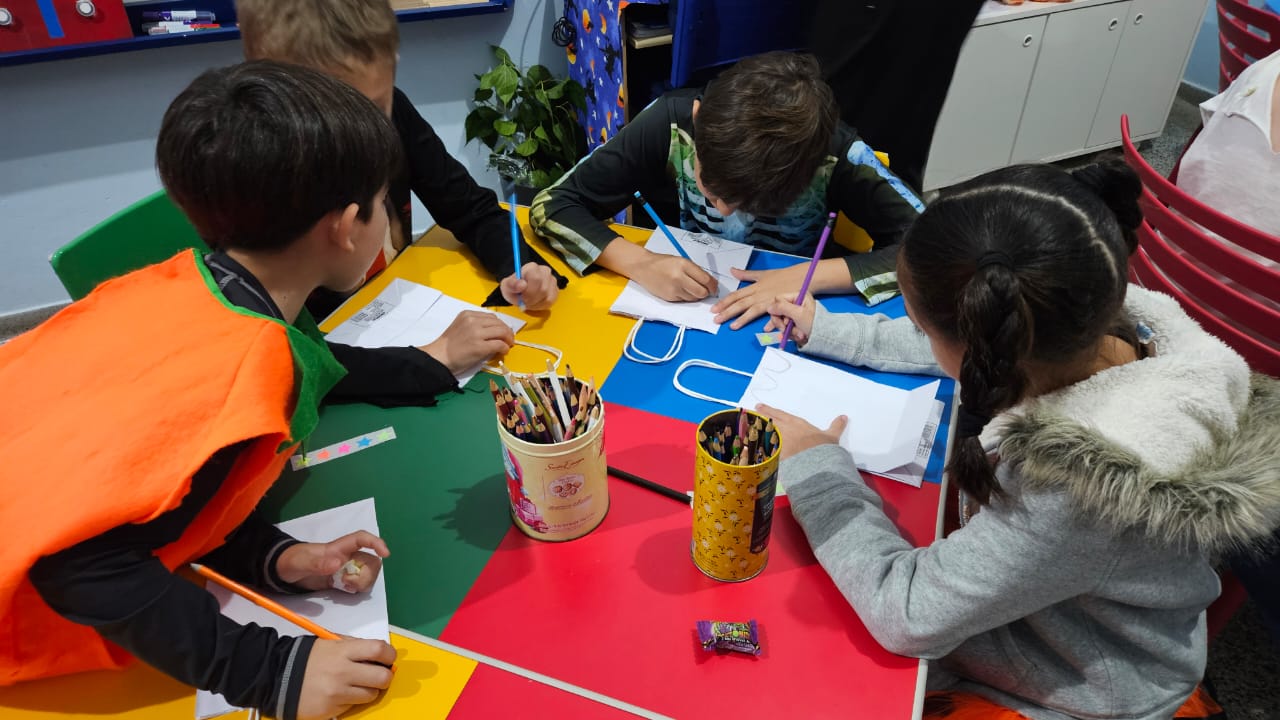 Crianças desenhando e escrevendo em inglês em atividade de grupo