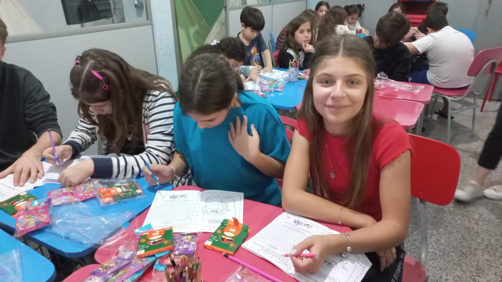 Alunas resolvendo atividades de inglês em mesas coloridas